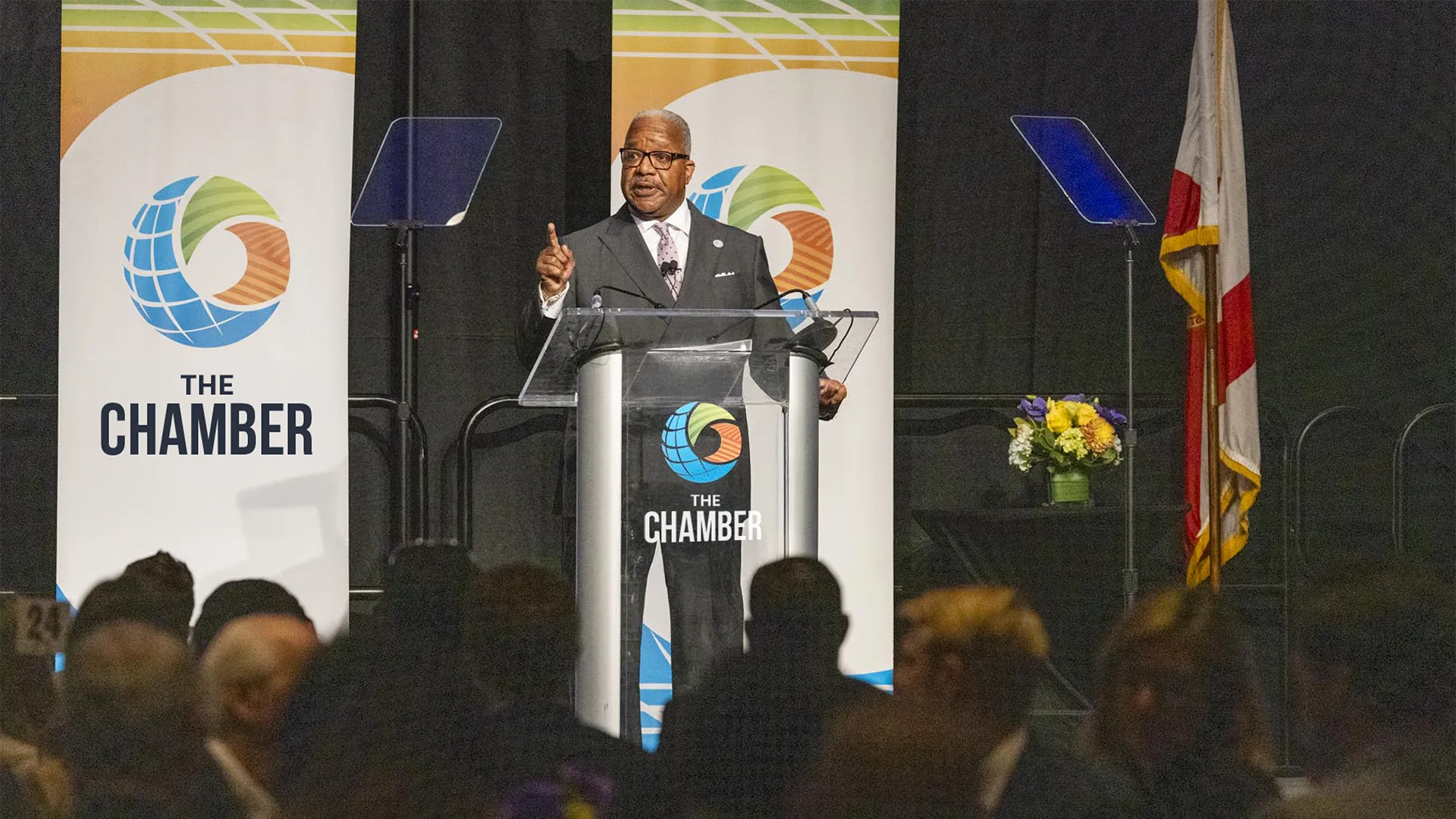 Mayor of West Palm Beach speaks on stage at Chamber event.