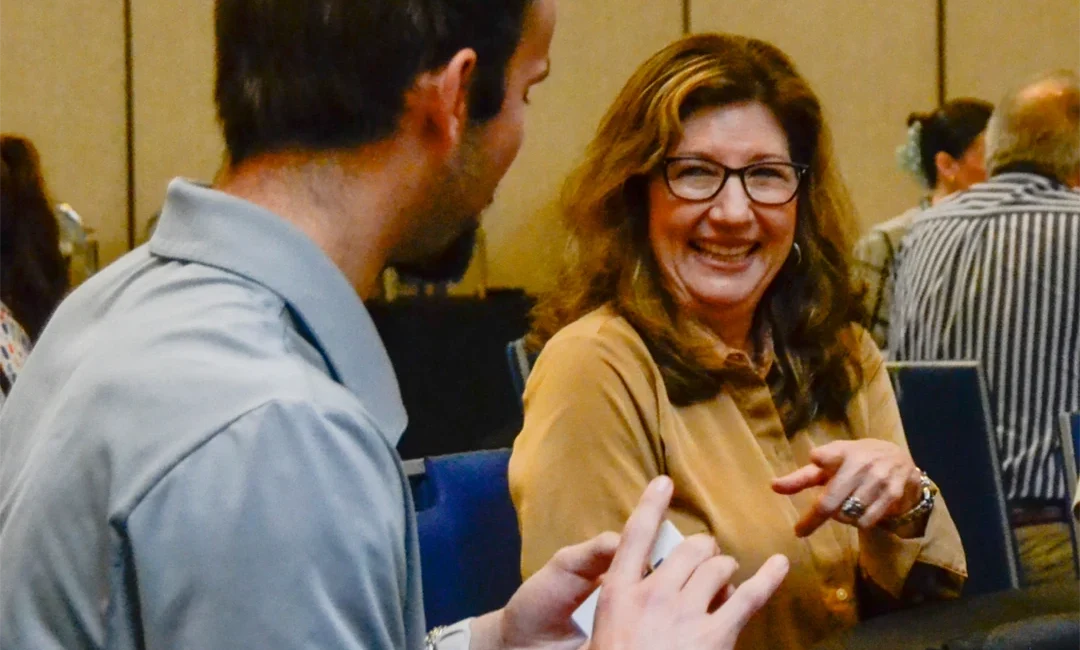 Man and woman engaged in conversation while sitting at a table.