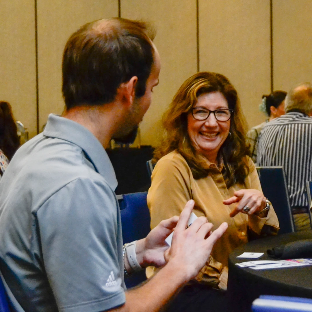 Man and woman engaged in conversation while sitting at a table.