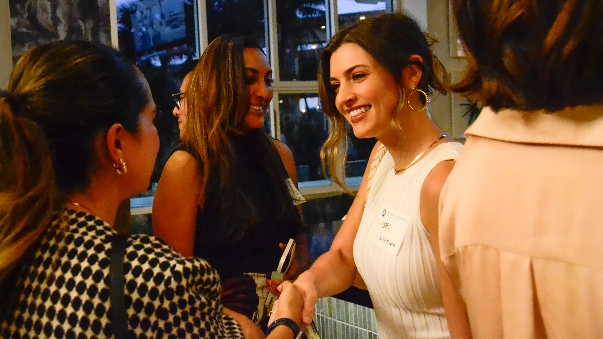 Several women exchanging handshakes at an event.